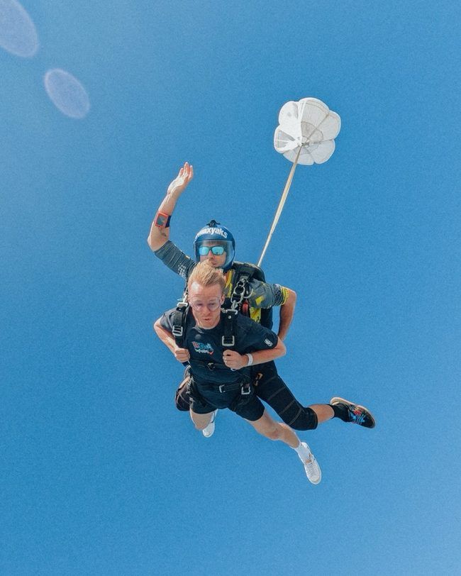 Nathan in freefall on a tandem skydive under a clear blue sky
