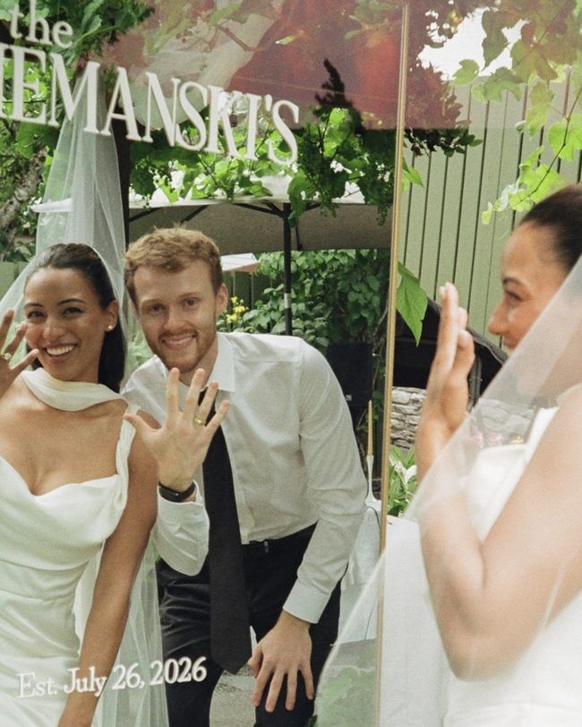 Nathan and Keasha showing their rings under a sign reading The Ziemanski’s on their wedding day