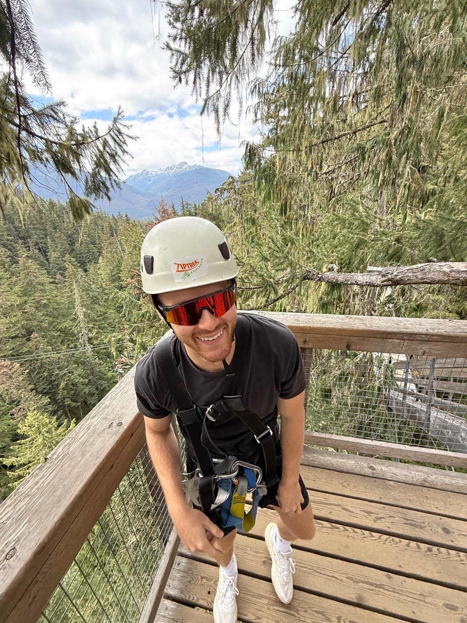 Nathan in a helmet and harness on a zipline platform above the forest in Whistler